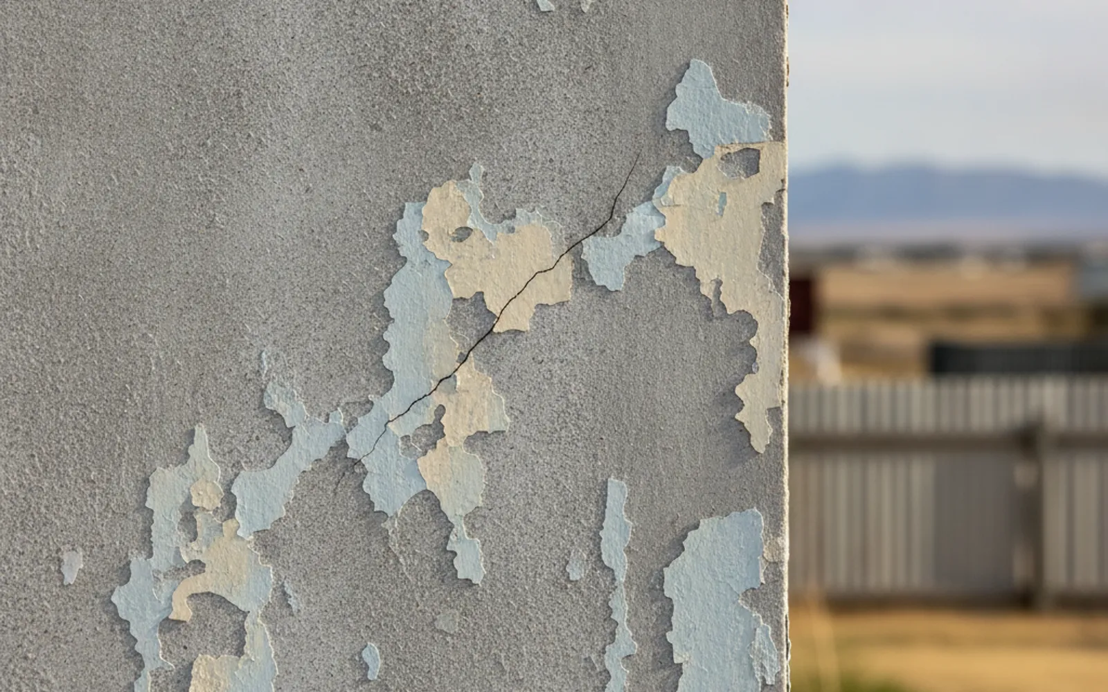 Cracked and weathered fibre cement sheeting on an exterior house wall